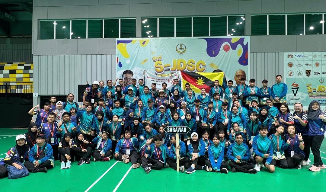 Group of Special Olympics athletes celebrating together with raised arms in a stadium
